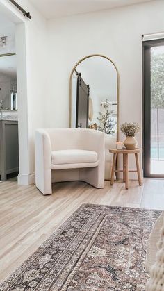 a white couch sitting on top of a hard wood floor next to a table and mirror