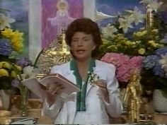 a woman standing in front of a table holding a piece of paper and wearing a green tie