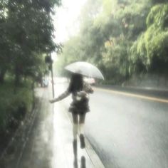 a woman walking down the street in the rain with an umbrella