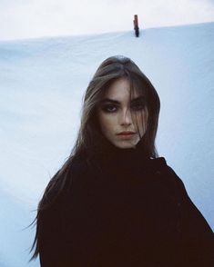 a woman with long hair standing in the snow