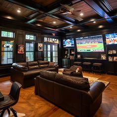 Ultimate man cave featuring luxurious black leather couches, dark wood paneling, and wood floors. Equipped with big screen TVs playing baseball, a bar with stools overlooking a scenic view, and cozy high ceilings. Perfect for sports fans with a minimalist, masculine design, this space includes an island bar for entertainment and built-in cabinets for storage. Man Cave Tv Setup, Man Cave Minimalistic, Man Basement Ideas, Moody Sports Basement, Man Cave Movie Room, Men’s Lounge, Cozy Rec Room, Basement Whiskey Lounge, Man Cave Tv Wall