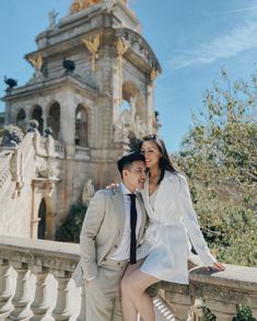 a man and woman posing for a photo on a balcony with a clock tower in the background