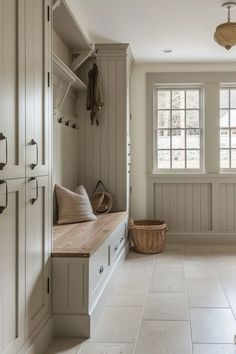 a large white kitchen with wooden cabinets and drawers on the wall next to a window