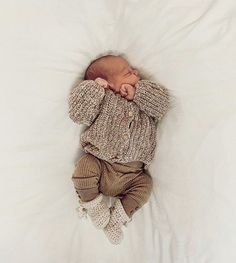 a baby laying on top of a white blanket