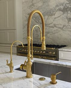 a kitchen with marble counter tops and gold faucets on the sink, in front of an oven