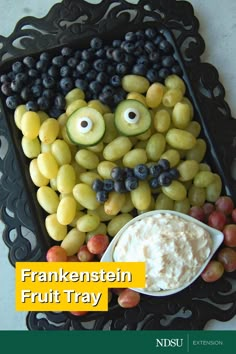 a tray with grapes, cucumbers and other fruit arranged in the shape of a face