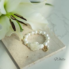 Charming Customizable Flower Girl Bracelet with Pearl Rose Centerpiece Make your flower girl feel extra special with this enchanting bracelet, thoughtfully designed to add a touch of elegance and personal charm to her ensemble. At the heart of this exquisite piece sits a large, light pink rose bead, symbolizing the blooming love and joy of your special day. This central rose is flanked by a strand of lustrous glass pearls, each one carefully selected for its soft glow and flawless finish, mirror Flower Shaped Stretch Bracelet For Gift, Flower Shaped Stretch Bracelet As Gift, White Flower Bracelets For Mother's Day, Elegant Beaded Bracelets With Flower Charm And Round Beads, White Flower Bracelet For Mother's Day, Flower-shaped Stretch Bracelet As Gift, Adjustable Pearl Bracelet With Flower Shape, Adjustable White Charm Bracelet With Flower Charm, White Flower Charm Bracelet For Wedding