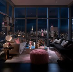 a living room filled with furniture and large windows overlooking the city lights at night time