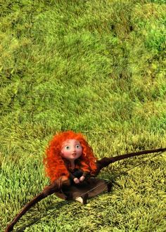 a red haired doll sitting on top of a grass covered field next to a bird