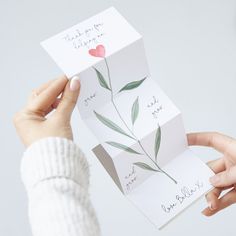 a woman holding up some cards with flowers on them