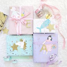 four wrapped presents with unicorns and stars on them are sitting on a white surface