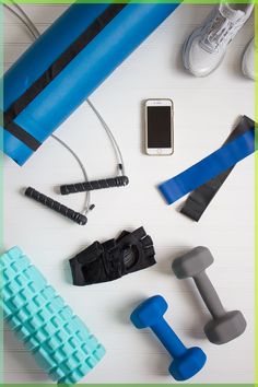 an assortment of exercise equipment laid out on top of a white table next to a cell phone