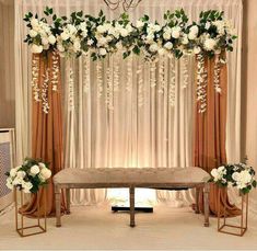 an elegant wedding setup with white flowers and greenery on the back of a bench