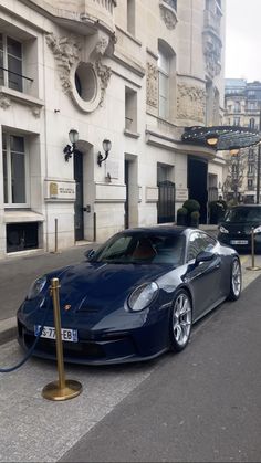 a blue sports car parked in front of a building on the side of a street