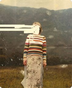 a woman standing in the middle of a field with mountains in the backgroud