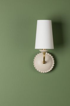 a small white lamp on a green wall