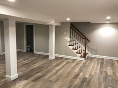 an empty living room with stairs and hard wood flooring in the middle of it