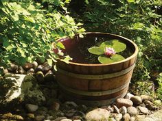 a wooden barrel filled with water and a pink flower floating in the middle of it