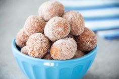 a blue bowl filled with sugar covered donuts