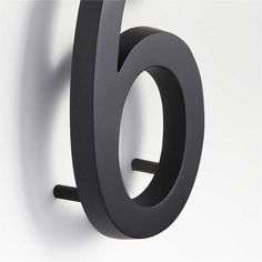 the number six is mounted to the wall and has black metal rings on it's sides