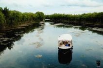 a small boat floating on top of a lake surrounded by trees and bushes in the distance