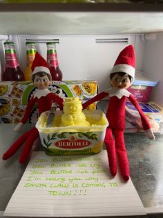 two elfs sitting on top of a refrigerator next to an ice cream sundae