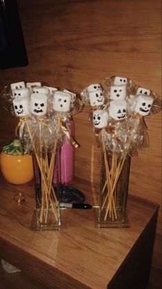 two vases filled with marshmallow heads on top of a wooden table