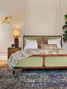 a large bed sitting on top of a blue rug next to a wooden dresser and lamp