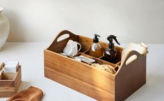 a wooden box with soap and lotion in it on a table next to a vase