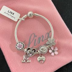 Linx Snake Chain Style Charm Bracelet With A Ball Clasp, Featuring Linx Logo. The Bracelet Comes With 7 Linx Charms As Shown. *All Items Are 925 Sterling Silver. *Guaranteed Authentic. *Linx Bracelets And Charms Are Very Well Made And Of Superior Quality, Designed To Last. These Pieces Come With A 100% Satisfaction Guarantee Or Your Money Back. *The Bracelet Is Available In Multiple Sizes *Additional Charms Can Also Be Added To The Bracelet And The Ones Included Are Removable As Well. *Linx Brac Mother's Day Metal Charm Bracelet, Pink Stainless Steel Jewelry With Charms, Pandora Charm Bracelet Pink, White Gold Bracelet For Mother's Day, Mother's Day White Gold Bracelet, Personalized Silver Snake Chain Jewelry, Silver Metal Charm Bracelet With Box Chain, Silver Metal Charm Bracelet With Silver Beads, Silver Chain Jewelry For Mother's Day