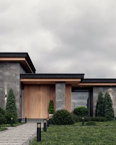 a modern house with large windows and wooden doors on the front lawn, surrounded by green grass