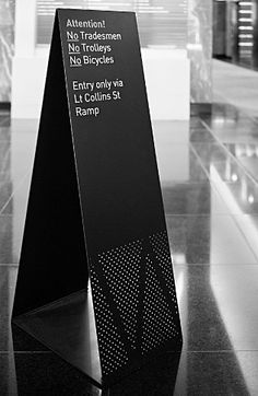 a black and white photo of a sign on the floor in a building with windows