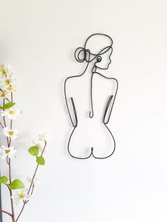 there is a wire sculpture on the wall next to a vase with flowers in it