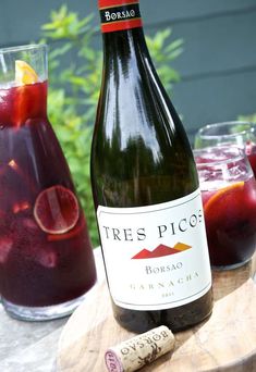 a bottle of wine sitting on top of a wooden table next to a glass filled with liquid