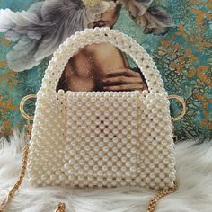 The beaded pearl bag with handle and shoulder strap is a sophisticated and versatile accessory that combines the timeless beauty of pearls with a practical design. This bag features exquisite beads, resembling pearls, meticulously crafted into a stunning pattern, creating a luxurious and elegant look. The bag is designed with both a handle and a shoulder strap, allowing for versatile carrying options to suit your preference and needs. Whether you choose to hold it by the handle or wear it on you Elegant White Bags With Pearl Chain, White Pearl Bag With Pearl Chain, Rectangular Pearl Evening Bag With Pearl Embroidery, White Bags With Pearl Chain, Pearl Evening Bag With Pearl Handle For Events, Evening Bags With Pearl Chain, White Evening Bag With Pearl Handle, Cream Pearl Evening Bag With Pearl Handle, Elegant Gold Pearl Shoulder Bag