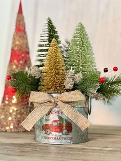 a tin can with christmas trees in it on top of a wooden table next to other decorations