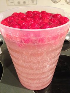 a large glass filled with raspberries on top of a stove