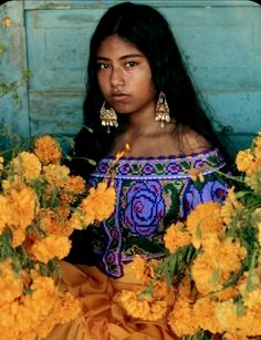 a young woman sitting in front of yellow flowers