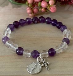 "Item details Handmade Materials Gemstone: 8mm Amethyst, Clear Quartz, Miraculous Medal, small ornate cross, Durable high quality stretch cord Rosary Bracelet for Women Stretch Bracelets, Miraculous Medal and small cross  The size of the bracelet is 7 inches.  May  request for a bigger or smaller size but the bead and spacer size will vary depending on requested size. This will be a great gift for confirmation!  A unique and beautiful personalized rosary bracelet!  It will make a perfect religious themed gift or inspiration for yourself. The beads used on every piece are handpicked. We make sure that each bracelet includes a range of the natural colors found in the stone It is not guaranteed to look exactly the same as shown in pictures but we promise it will be just as pretty! To find you Spiritual Rosary Bracelet With Gemstone Beads, Adjustable Purple Rosary Bracelet, Adjustable Purple Spiritual Rosary Bracelet, Handmade Spiritual Purple Rosary Bracelet, St Bridget, Ornate Cross, Personalized Rosary, Rosary Bracelet, Stretch Band