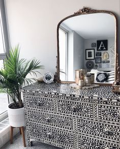 an ornate dresser with a mirror and potted plant