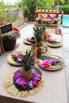 pineapples and other tropical decorations are on the table by the pool for an outdoor party