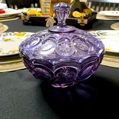 a purple glass bowl sitting on top of a table