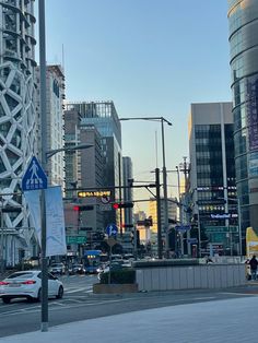 a city street with tall buildings in the background and cars driving on it's sides