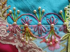 three embroidered flowers and pearls on a piece of fabric with pink gingham checkered table cloth