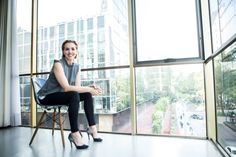 a woman sitting on a chair in front of a window with the city outside her