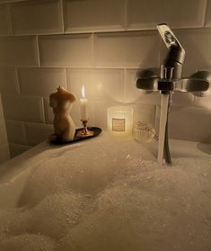 a bathtub filled with foam next to a candle