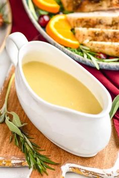 a bowl of soup on a plate with bread and oranges in the back ground