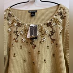 a sweater with beading and pearls hanging on a hanger