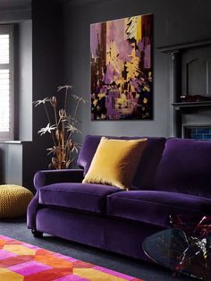 a living room with purple couches and colorful rugs