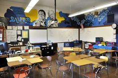 an empty classroom with desks and chairs in front of a chalkboard mural on the wall